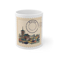 White 11oz ceramic mug featuring a vintage postage stamp illustration of a Kyoto skyline in watercolor with a navy postmark.