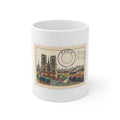 11oz white ceramic mug featuring a vintage perforated postage stamp illustration of the Paris skyline with a navy postmark.